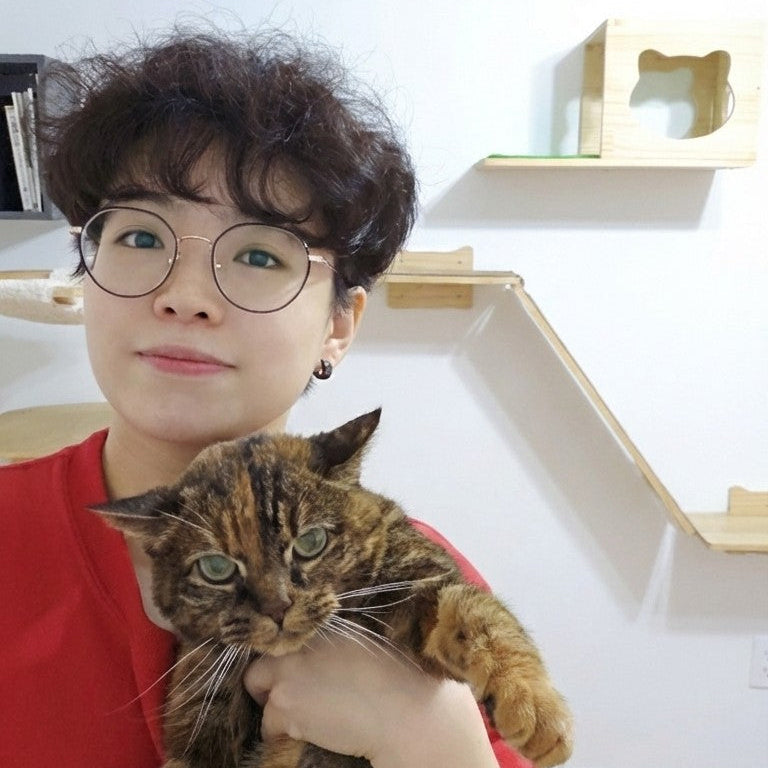 Kay, cofounder of Pawsy Pals, holding her tabby cat Sanner — the inspiration behind our custom pet portrait phone accessories